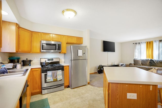 kitchen featuring a kitchen breakfast bar, a center island, appliances with stainless steel finishes, and sink