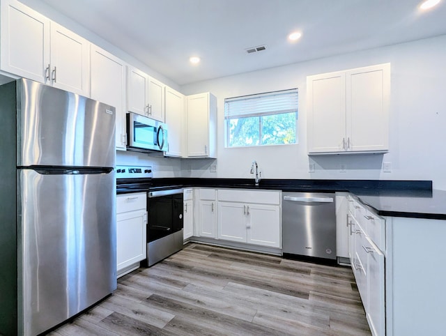 kitchen with appliances with stainless steel finishes, sink, light hardwood / wood-style floors, and white cabinets