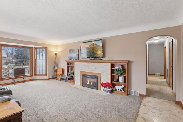 carpeted living room featuring a textured ceiling and a tiled fireplace