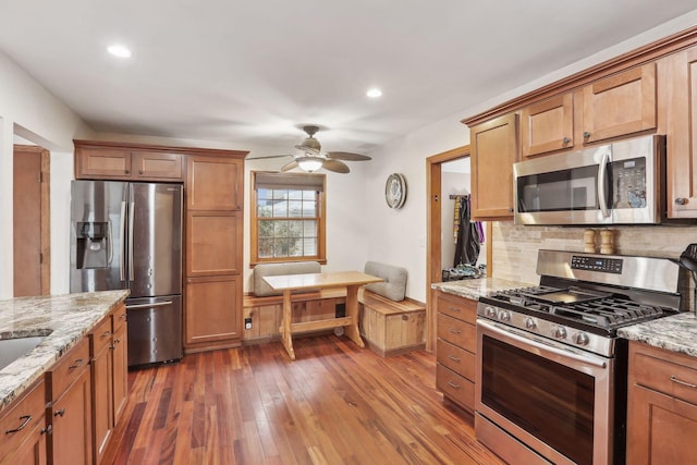 kitchen featuring backsplash, light stone counters, dark hardwood / wood-style flooring, and stainless steel appliances