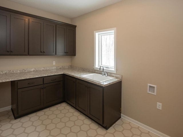 kitchen featuring light countertops, a sink, dark brown cabinets, and baseboards