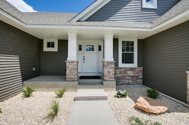 doorway to property featuring stone siding, a shingled roof, and a porch