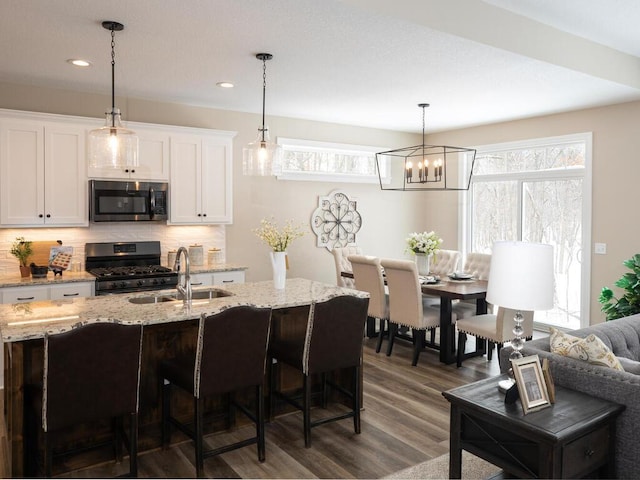 kitchen with white cabinets, decorative light fixtures, dark wood-type flooring, and black gas range