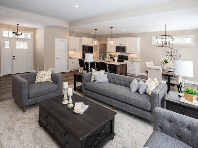 living room featuring light wood-type flooring, a healthy amount of sunlight, and a notable chandelier