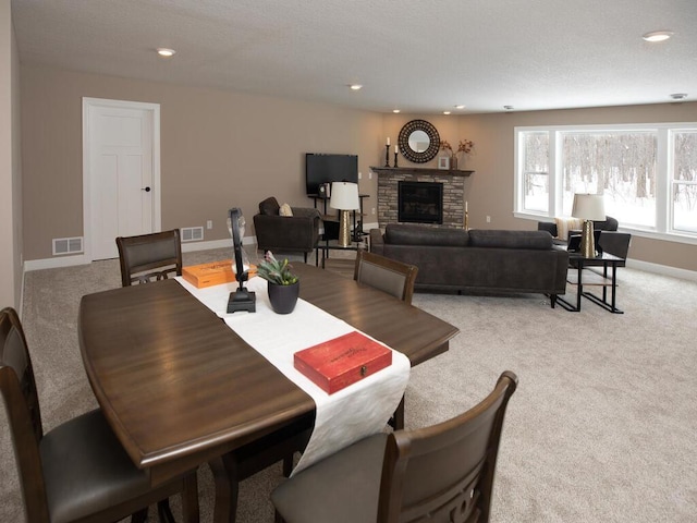 dining space with light carpet, baseboards, a fireplace, and visible vents