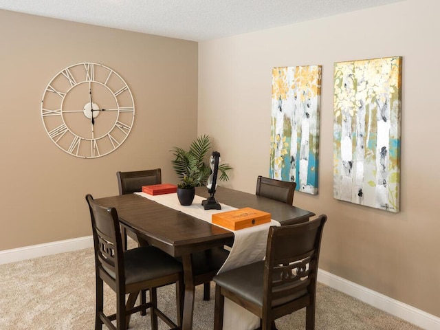 carpeted dining room featuring baseboards and a textured ceiling