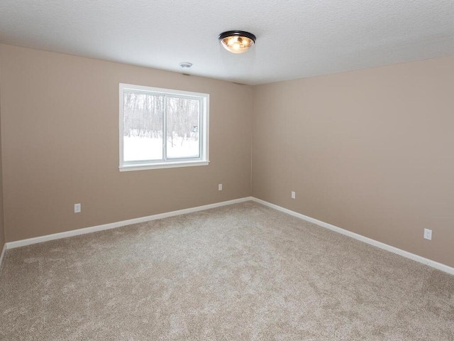 spare room featuring baseboards, carpet flooring, and a textured ceiling
