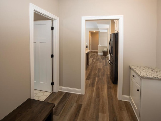 corridor featuring baseboards and dark wood-style floors