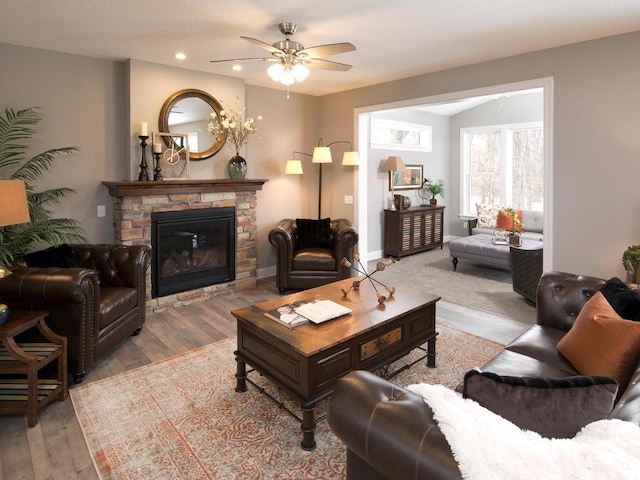 living room featuring ceiling fan, light wood-type flooring, and a fireplace