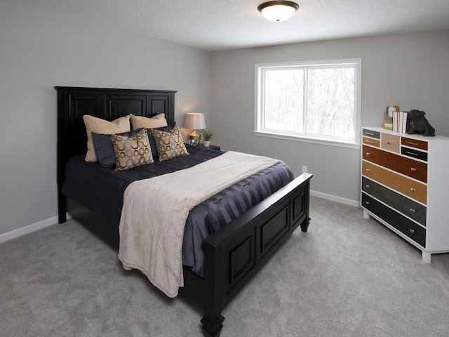bedroom with baseboards, light colored carpet, and a textured ceiling