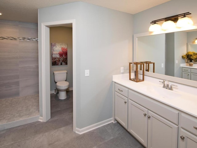 bathroom with a textured ceiling, a tile shower, vanity, and toilet