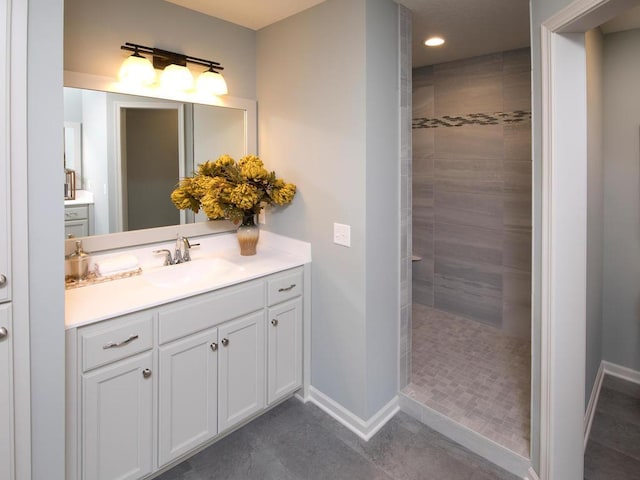 bathroom with tiled shower, vanity, and tile patterned flooring