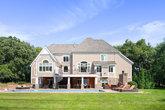 rear view of house featuring a patio, a balcony, and a lawn