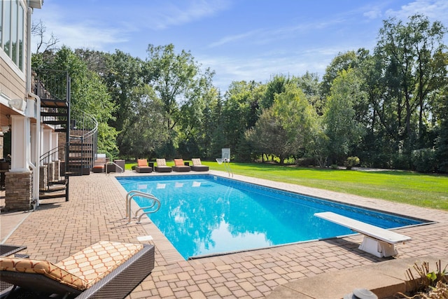 view of swimming pool featuring a patio area, a diving board, and a lawn