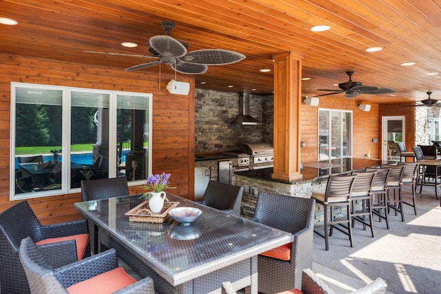 dining area with wood walls, wood ceiling, and ceiling fan