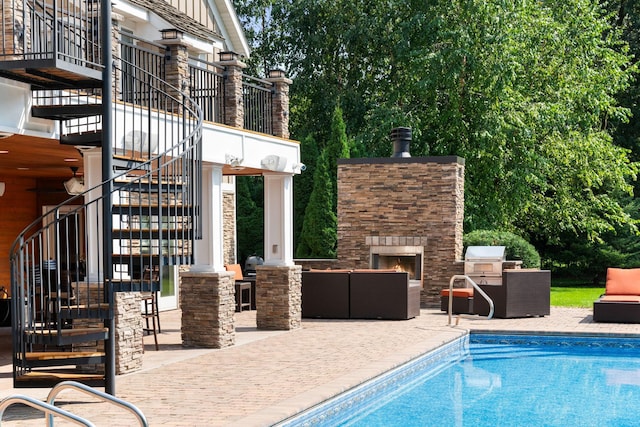 view of swimming pool with an outdoor stone fireplace and a patio area