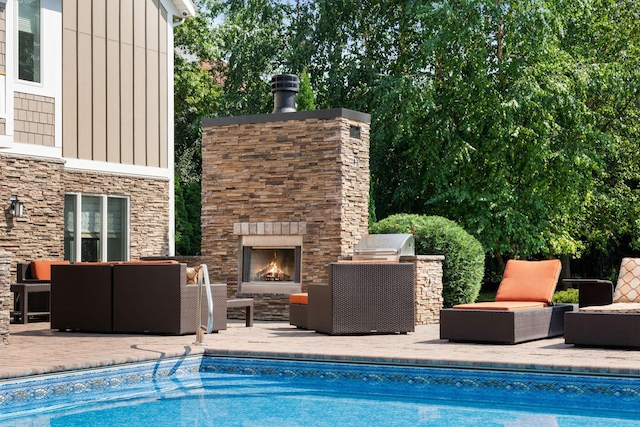 view of pool with a patio and an outdoor living space with a fireplace