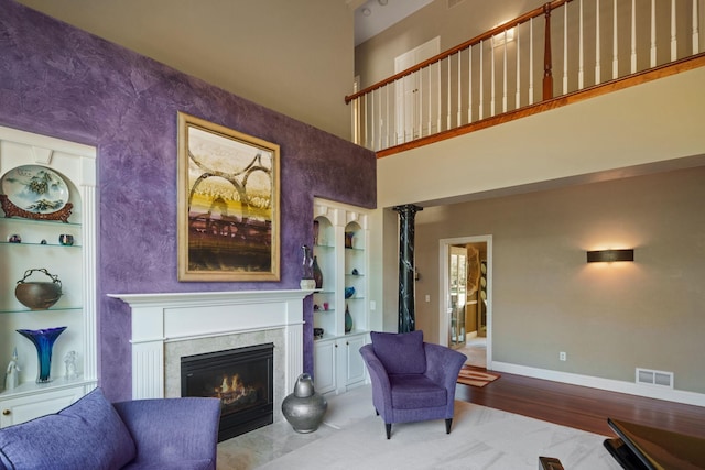 living area with built in features, a high ceiling, and hardwood / wood-style flooring