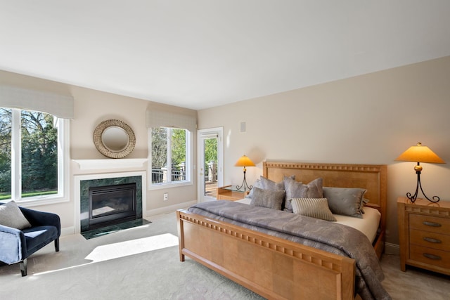 bedroom featuring a fireplace, light colored carpet, and multiple windows