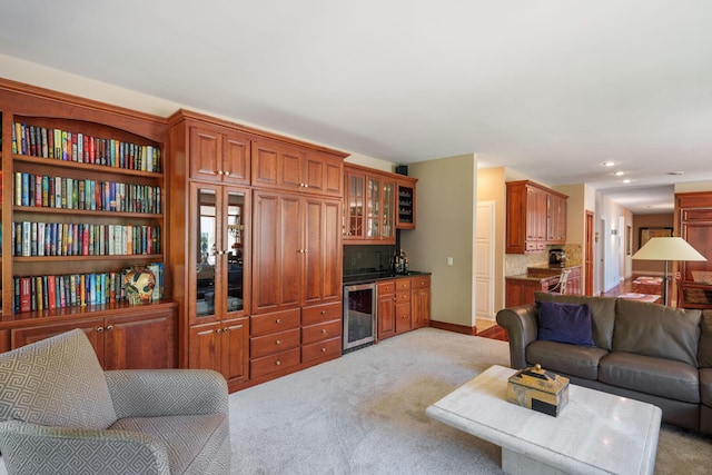 living room featuring beverage cooler, light colored carpet, and bar area