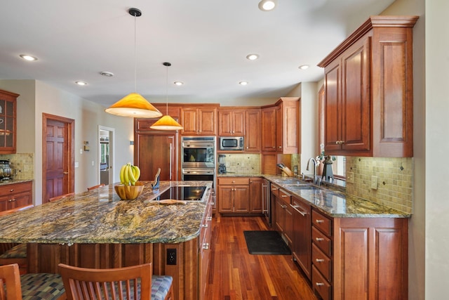 kitchen featuring a kitchen island with sink, dark hardwood / wood-style flooring, hanging light fixtures, appliances with stainless steel finishes, and a kitchen breakfast bar