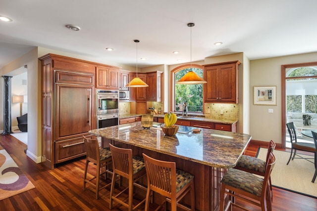 kitchen featuring pendant lighting, dark hardwood / wood-style floors, tasteful backsplash, and a kitchen island