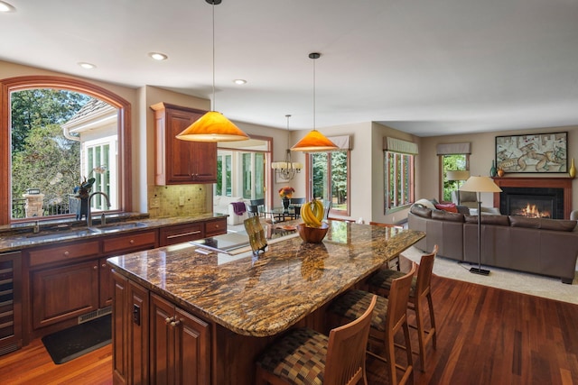 kitchen featuring dark wood-type flooring, a kitchen island, a wealth of natural light, and a breakfast bar