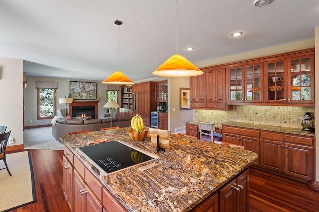 kitchen with black electric cooktop, a center island, dark wood-type flooring, stone counters, and backsplash