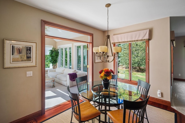 dining space with hardwood / wood-style floors and an inviting chandelier