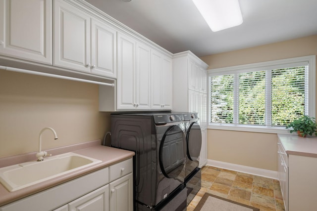 laundry area with washing machine and clothes dryer, cabinets, and sink