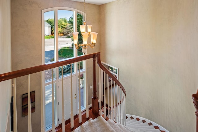 stairs featuring wood-type flooring and an inviting chandelier