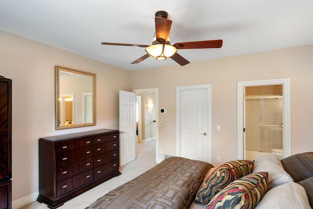 bedroom with ceiling fan, light colored carpet, and connected bathroom