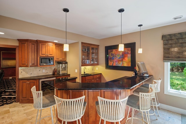 bar with beverage cooler, stainless steel microwave, decorative light fixtures, sink, and decorative backsplash