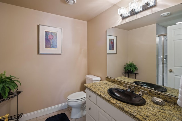 bathroom with tile patterned flooring, vanity, a shower with door, and toilet