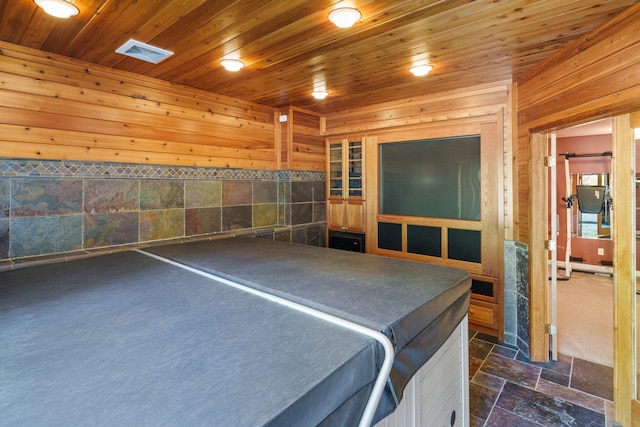 interior space with dark colored carpet, wood walls, tile walls, and wood ceiling