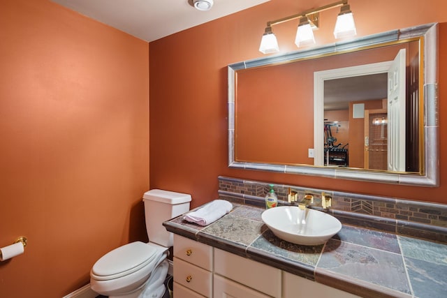 bathroom featuring vanity, backsplash, and toilet