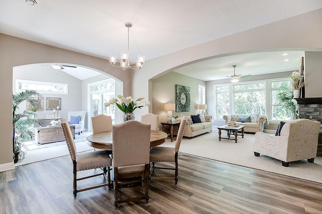 dining room with ceiling fan with notable chandelier, lofted ceiling, dark hardwood / wood-style floors, and a wealth of natural light