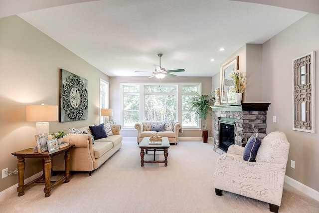 living room with carpet flooring, ceiling fan, a fireplace, and a textured ceiling