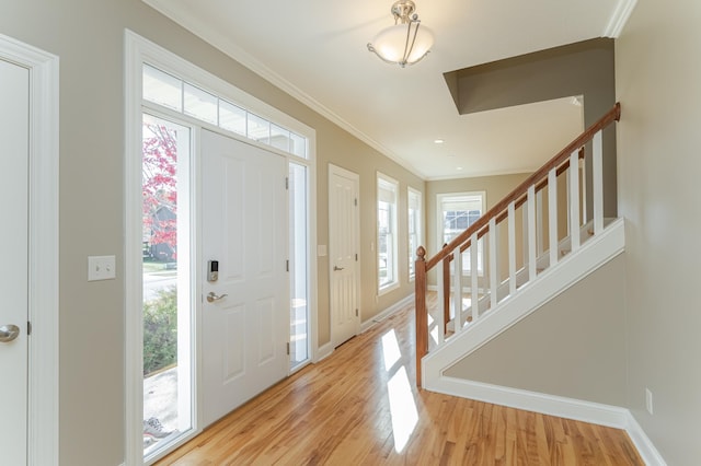 entrance foyer featuring ornamental molding, a healthy amount of sunlight, and light wood-type flooring