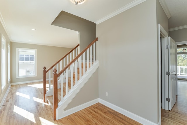 stairway with crown molding, hardwood / wood-style floors, and a wealth of natural light