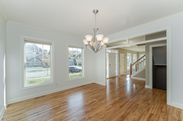 unfurnished dining area with crown molding, an inviting chandelier, and light wood-type flooring