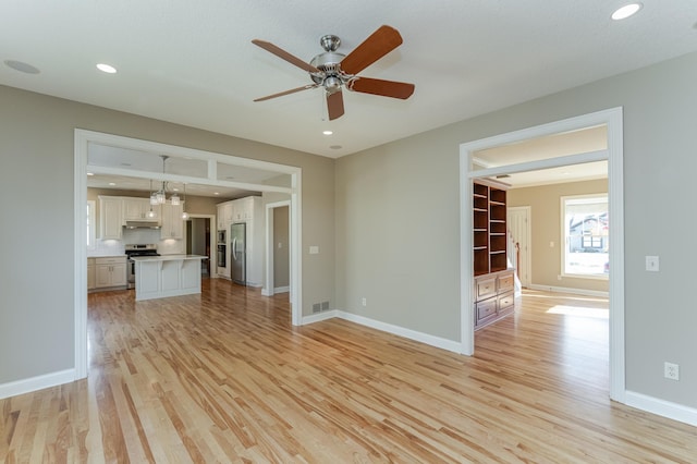 unfurnished living room featuring ceiling fan and light hardwood / wood-style flooring