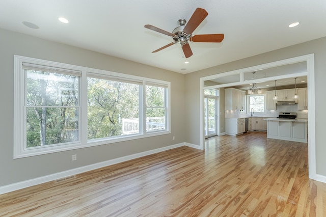 unfurnished living room with light hardwood / wood-style floors, sink, and ceiling fan