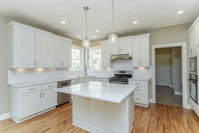 kitchen with appliances with stainless steel finishes, white cabinetry, light wood-type flooring, and a kitchen island