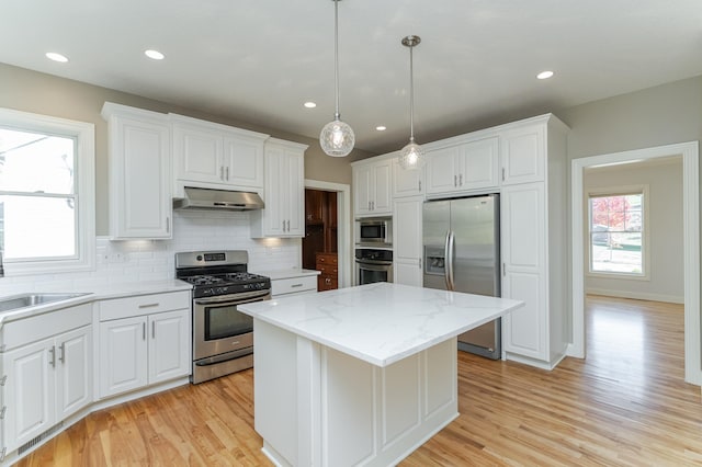 kitchen featuring appliances with stainless steel finishes, white cabinets, light hardwood / wood-style floors, and a kitchen island