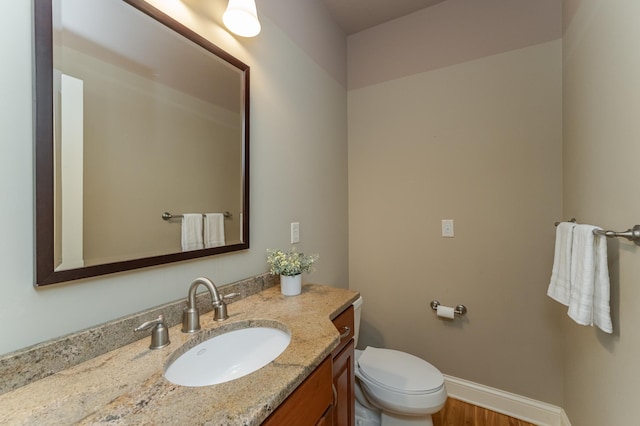 bathroom with toilet, hardwood / wood-style floors, and vanity