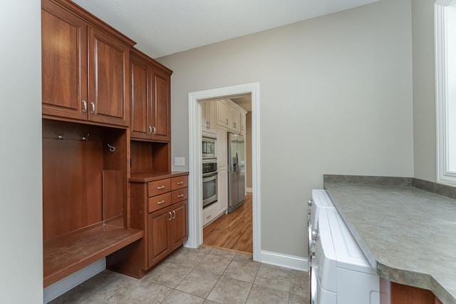 mudroom with light tile patterned floors and washer and clothes dryer