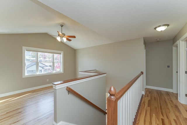 hallway with light wood-type flooring and vaulted ceiling