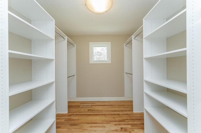 walk in closet with light hardwood / wood-style floors