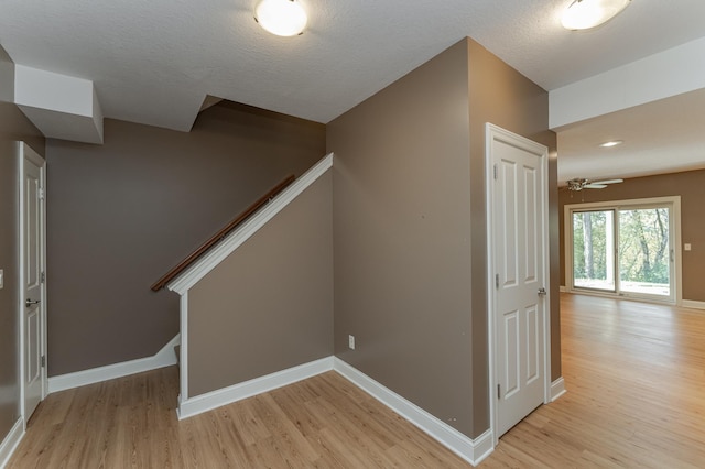 stairway featuring ceiling fan, hardwood / wood-style flooring, and a textured ceiling